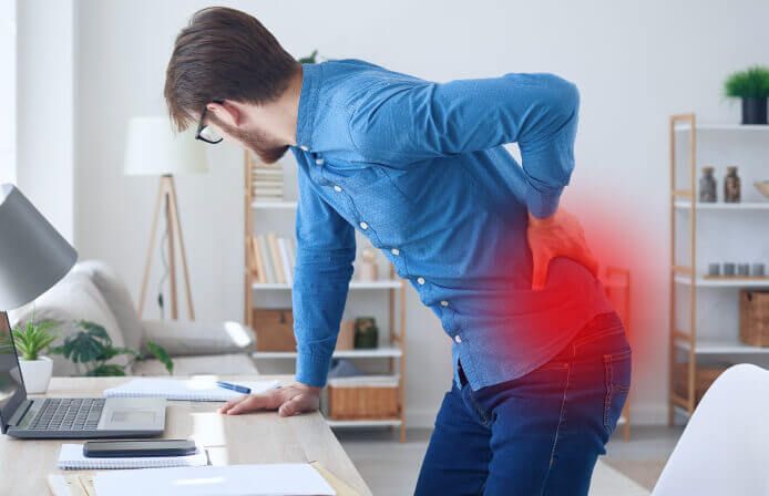 A young man with back pain holds his lower body