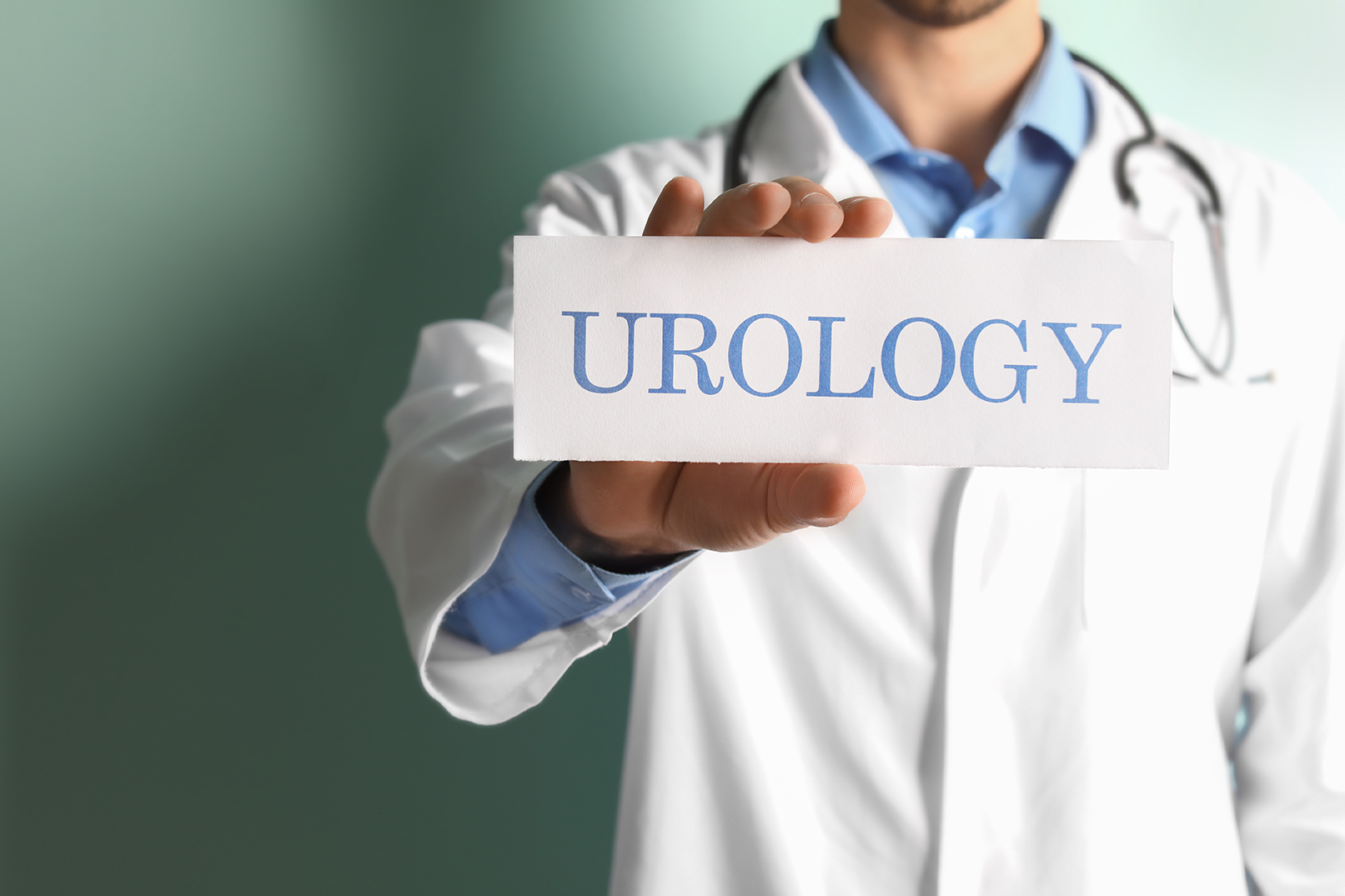A urologist holding up a sign that says “urology”