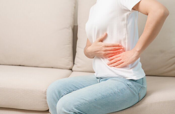 Woman having abdomen pain on the sofa at home